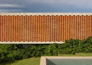 La fachada de ladrillo puntúa la casa de concreto de Fernanda Padula en Brasil