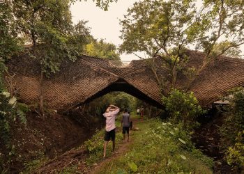 Wallmakers envuelve su 'casa puente' suspendida con escamas con techo de paja