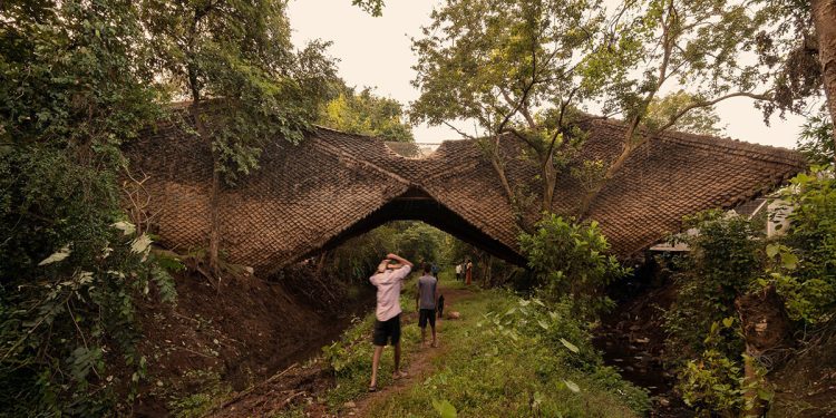 Wallmakers envuelve su 'casa puente' suspendida con escamas con techo de paja