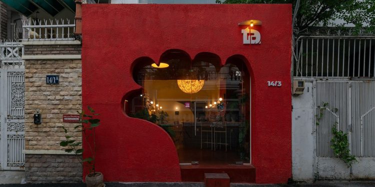 La fachada roja de un café talla una entrada con forma de mano en Vietnam